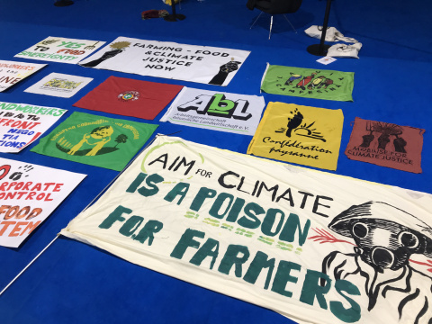 Banner challenging AIM for Climate with La Via Campesina banners Banner challenging AIM for Climate on floor with La Via Campesina banners